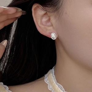 Close-up of S925 silver oval stud earring with beaded edge and sparkling center stone