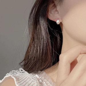 Close-up of minimalist silver 925 irregular bean-shaped earrings worn by a model