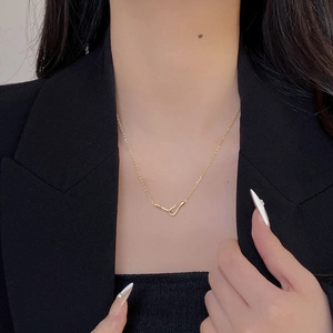Close-up of minimalist interlocking gold bar and hook pendant necklace on a model