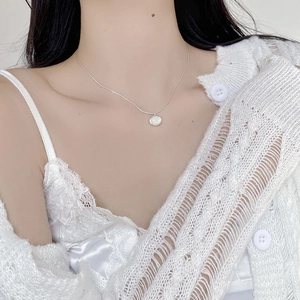Close-up of S925 sterling silver necklace with a white shell pendant on a model wearer