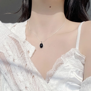 Close-up of 925 silver necklace with oval black agate pendant worn on a model's neck