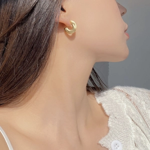 Close-up of a matte gold C-shaped S925 sterling silver earring on a female model