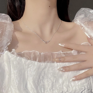Detail of interlocking V pendants on a fine silver necklace worn by a model in lace top