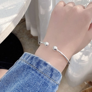 Detail view of a 925 sterling silver open bangle with polished double spheres on wrist