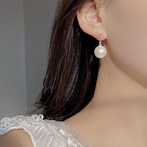 Macro view of S925 sterling silver pearl drop earrings on model for elegant style