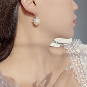 Close-up of elegant S925 silver hook earring with large round white pearl on model