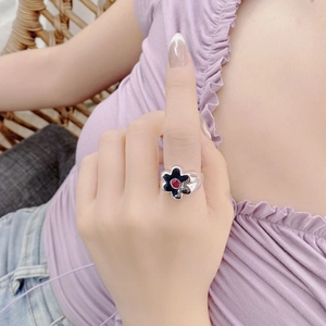 Detailed close-up of a silver flower ring with black petals and a red zircon stone