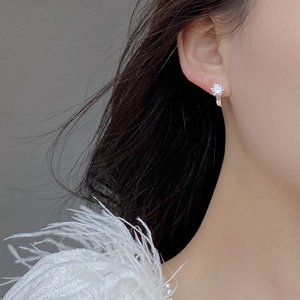Detailed close-up of a six-prong silver earring with a sparkling round zircon on ear