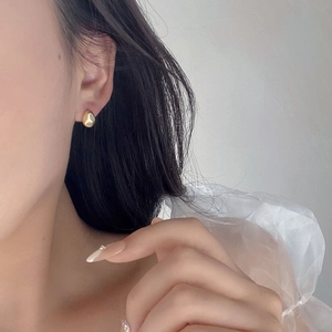 Close-up of elegant gold oval stud earrings with matte finish worn by a model