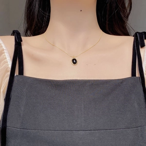 Close-up of minimalist 925 silver necklace with an oval black onyx pendant on neck