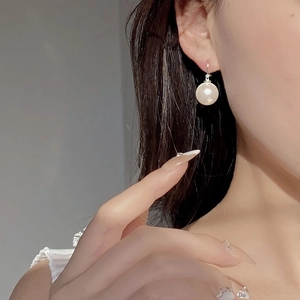 Detail of elegant S925 silver hoop earrings with a 10mm round white pearl on a model