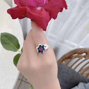 Detailed view of silver flower ring with black enamel and pink zircon on hand
