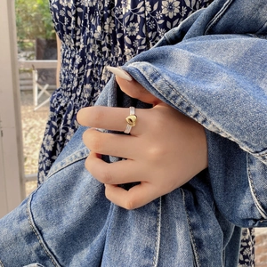 Detail of silver twisted band ring with a polished gold heart on finger