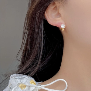 Detailed view of S925 silver six-prong cubic zirconia hoop earring worn on an ear