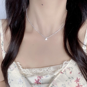 Gros plan d'un collier minimaliste en argent S925 avec un pendentif diamant vert éclatant