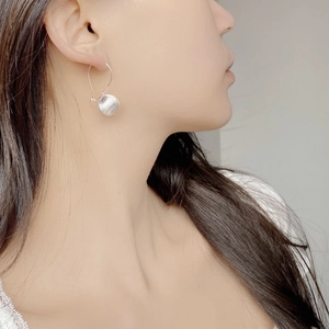 Close-up of S925 sterling silver earrings with a brushed spherical drop on a female model