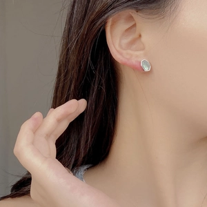 Close-up of geometric S925 silver hexagonal stud earrings with iridescent green shell inlay