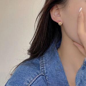 Close-up of elegant gold knotted hollow earrings worn by model for a stylish look