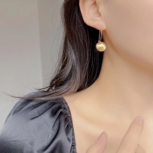 Minimalist matte gold ball earrings shown on a model with elegant black silk dress