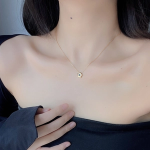Detailansicht einer goldenen Gänseblümchen-Kette mit schwarzem Zirkonia auf der Haut
