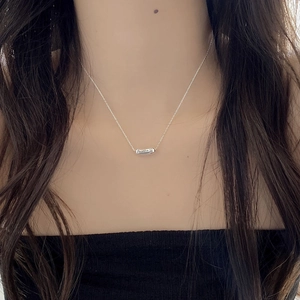 Close-up of silver minimalist capsule pendant with December 12 engraving on chain