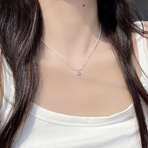 Gros plan détaillé d'un pendentif en pierre rose sur une fine chaîne en argent S925 portée par mannequin