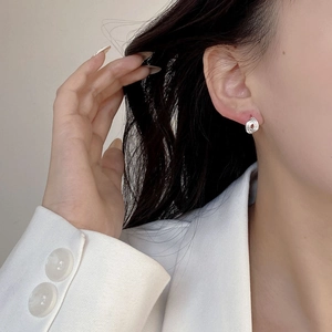 Detail of twisted silver geometric stud earring worn by model in white suit