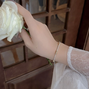 Detailed shot of 925 silver beaded bracelet with gold accents held against a white rose