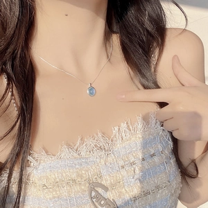 Close-up of S925 silver necklace with oval aquamarine pendant on female model neck