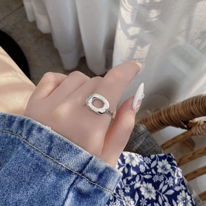 Gros plan d'une bague géométrique évidée en argent S925 portée au doigt style vintage