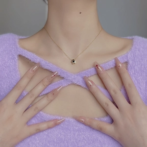 Nahaufnahme der goldenen Gänseblümchen-Halskette mit schwarzem Zirkonia-Anhänger am Model