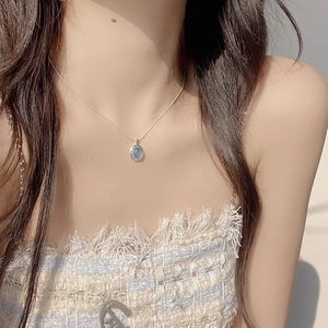 Detail shot of an oval light blue aquamarine pendant on a slender silver chain for women