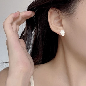 Detail of silver hexagonal shell stud earrings worn by a model for elegant styling