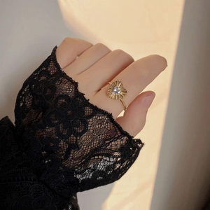 Detail of pleated gold heart ring with white zircon on black lace background