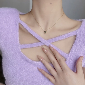 Detail einer minimalistischen Goldkette mit Gänseblümchen-Anhänger und schwarzem Stein