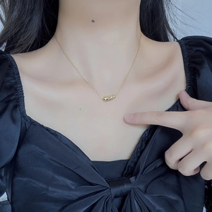 Close-up of a minimalist gold pea pendant necklace on a model's collarbone