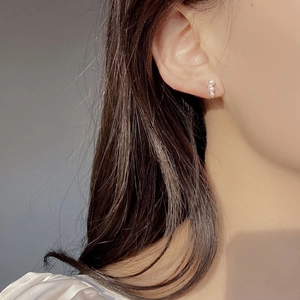 Close-up of triple pearl vertical drop earrings worn by a model in natural light