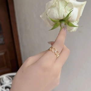 Détail d'une bague géométrique dorée minimaliste avec maillons évidés sur le doigt
