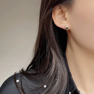 Nahaufnahme minimalistischer Herz-Ohrstecker mit schwarzem Kern und Goldrand an Model