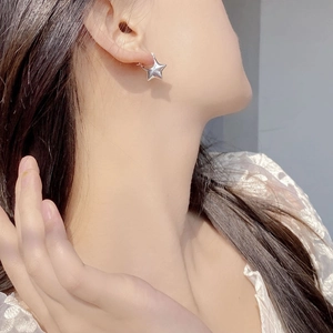 Close-up of a model wearing a polished S925 sterling silver star-shaped hoop earring
