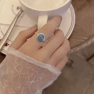 Close-up of S925 silver ring with oval aquamarine stone worn by a woman at tea time