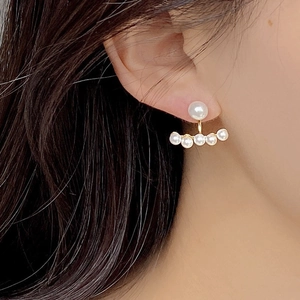 Detail of 925 silver pearl stud earrings with a golden arch of five small pearls