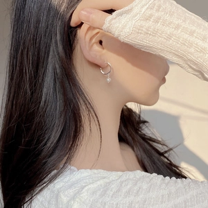 Dettaglio di un orecchino a C minimalista con perla d'acqua dolce su una modella femminile