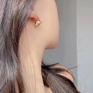 Chic 3D star-shaped earrings in polished gold finish worn on female model's ear