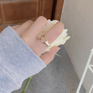 Detailansicht eines asymmetrischen goldenen Rings mit geometrischer U-Form am Finger