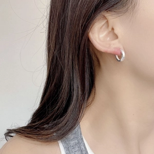 Close-up of minimalist brushed silver hoop earrings worn on ear with a clean look