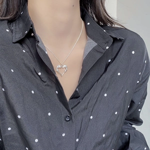 Close-up of S925 sterling silver hollow heart and angel wing pendant on a woman