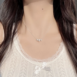 Detail of S925 sterling silver brushed bean necklace worn on neck with white lace top