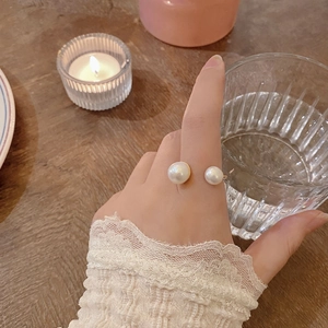 Detail of U-shaped gold ring with dual freshwater pearls worn on index finger