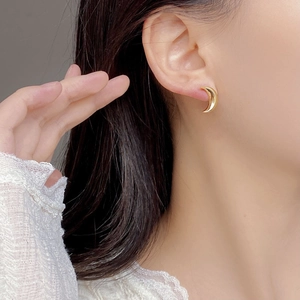 Close-up of elegant crescent moon gold silver earrings worn on the earlobe